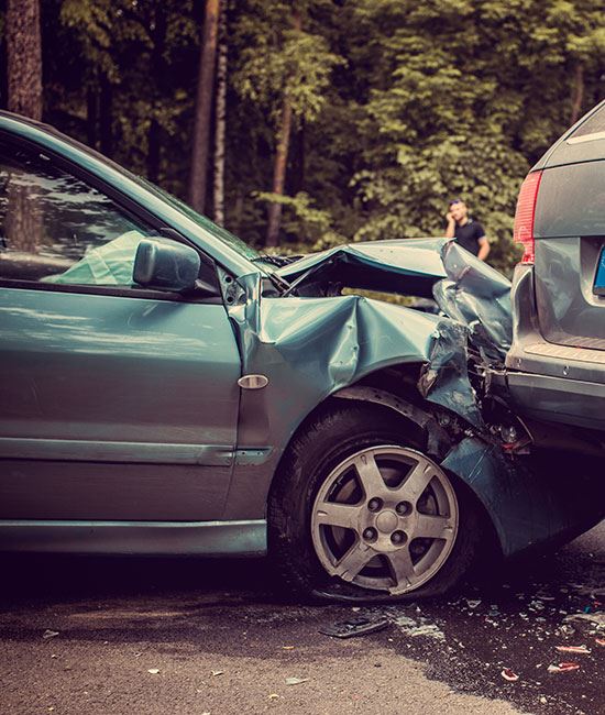 Photo of a fender bender accident with man in background using his cell phone to call for assistance
